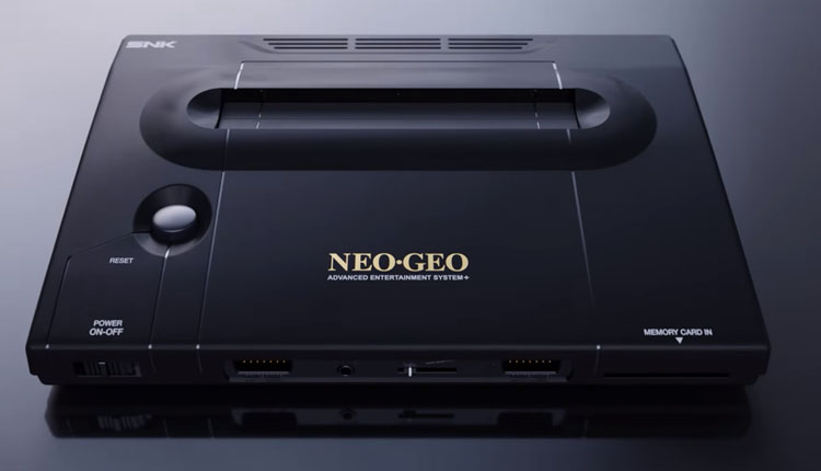 Top‑down view of a black Neo‑Geo AES console with a large cartridge slot on top, power and reset buttons on the left, and front ports.